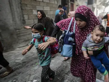 Mujeres y niños palestinos huyen tras un ataque aéreo israelí en la ciudad de Gaza.