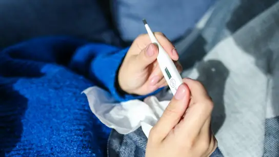 Imagen de archivo de una persona con un termómetro Expertos esperan una vuelta a la normalidad de la gripe con un solo pico en todo el invierno