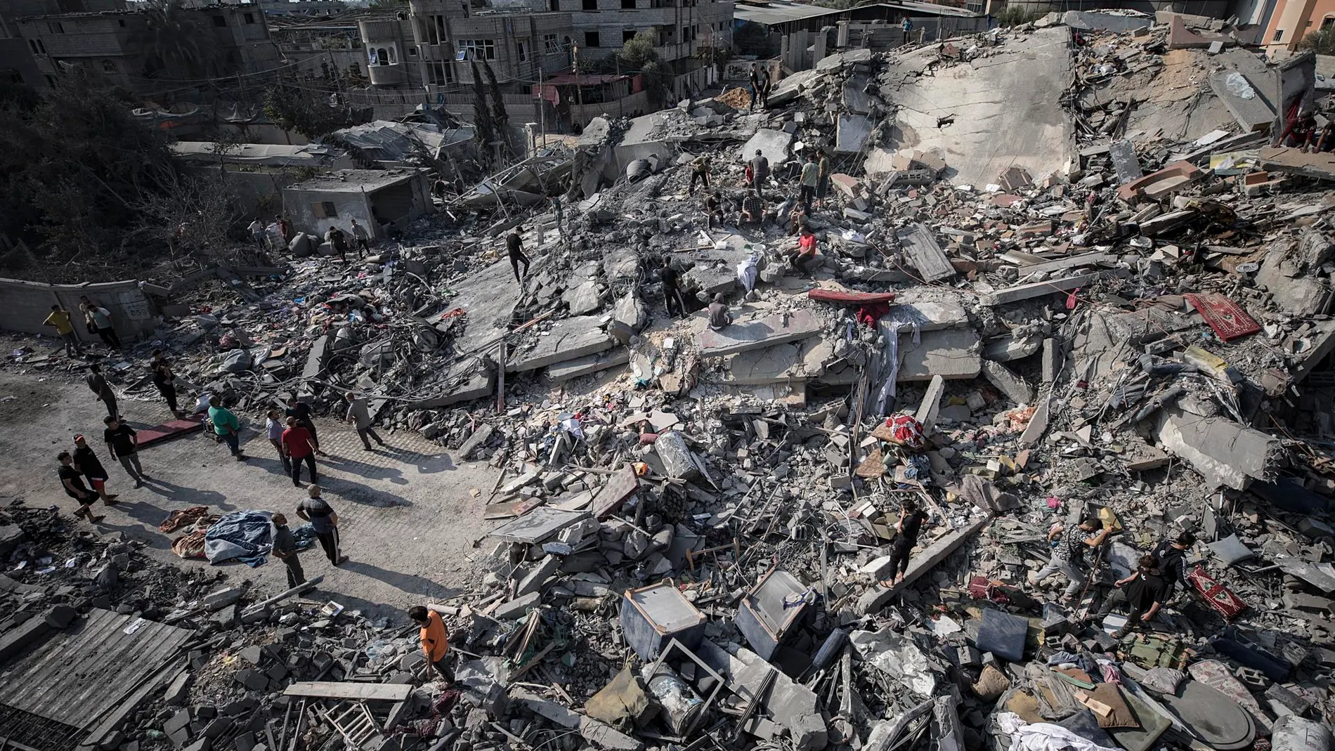 Palestinos buscan cadáveres y supervivientes bajo los escombros de un edificio residencial tras un ataque aéreo israelí contra el campo de refugiados de Nuseirat.