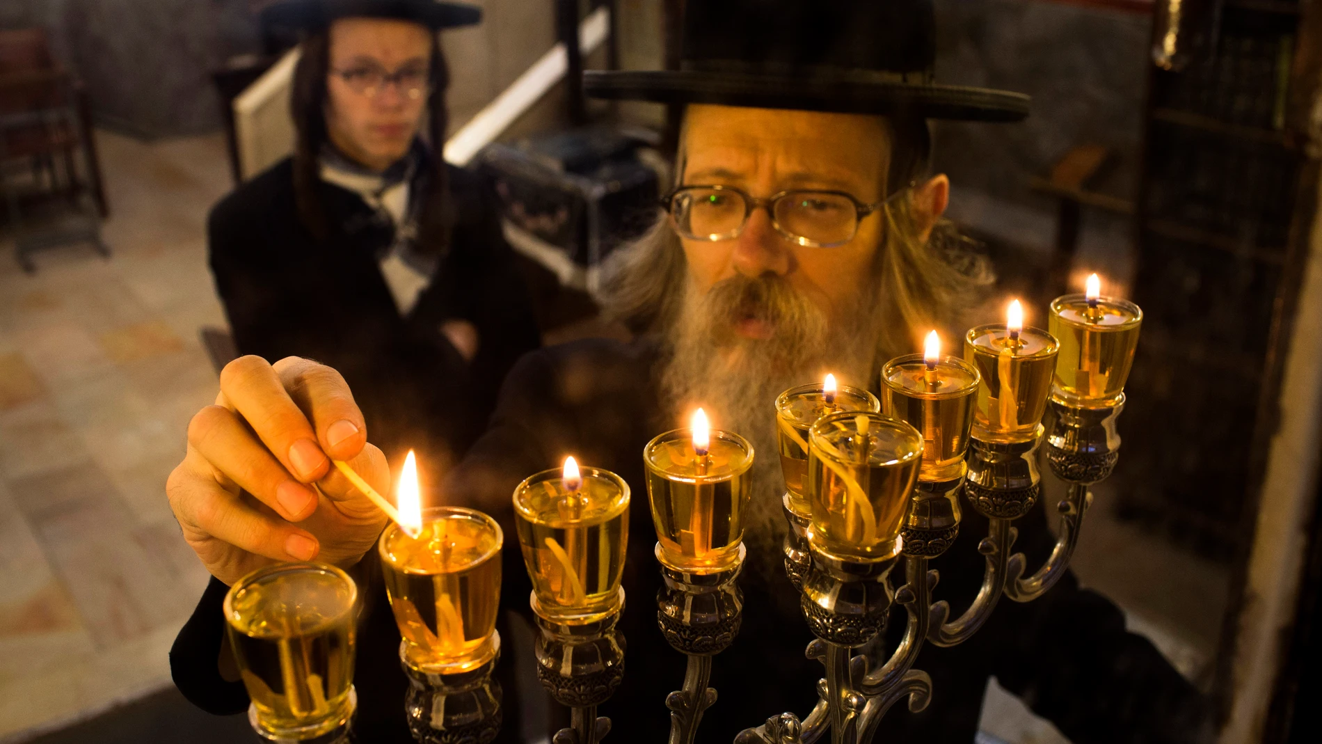 Un judío ultraortodoxo encendiendo una vela en la menorá el último día de Jánuca en el barrio de Mea Shearim de Jerusalén en 2013