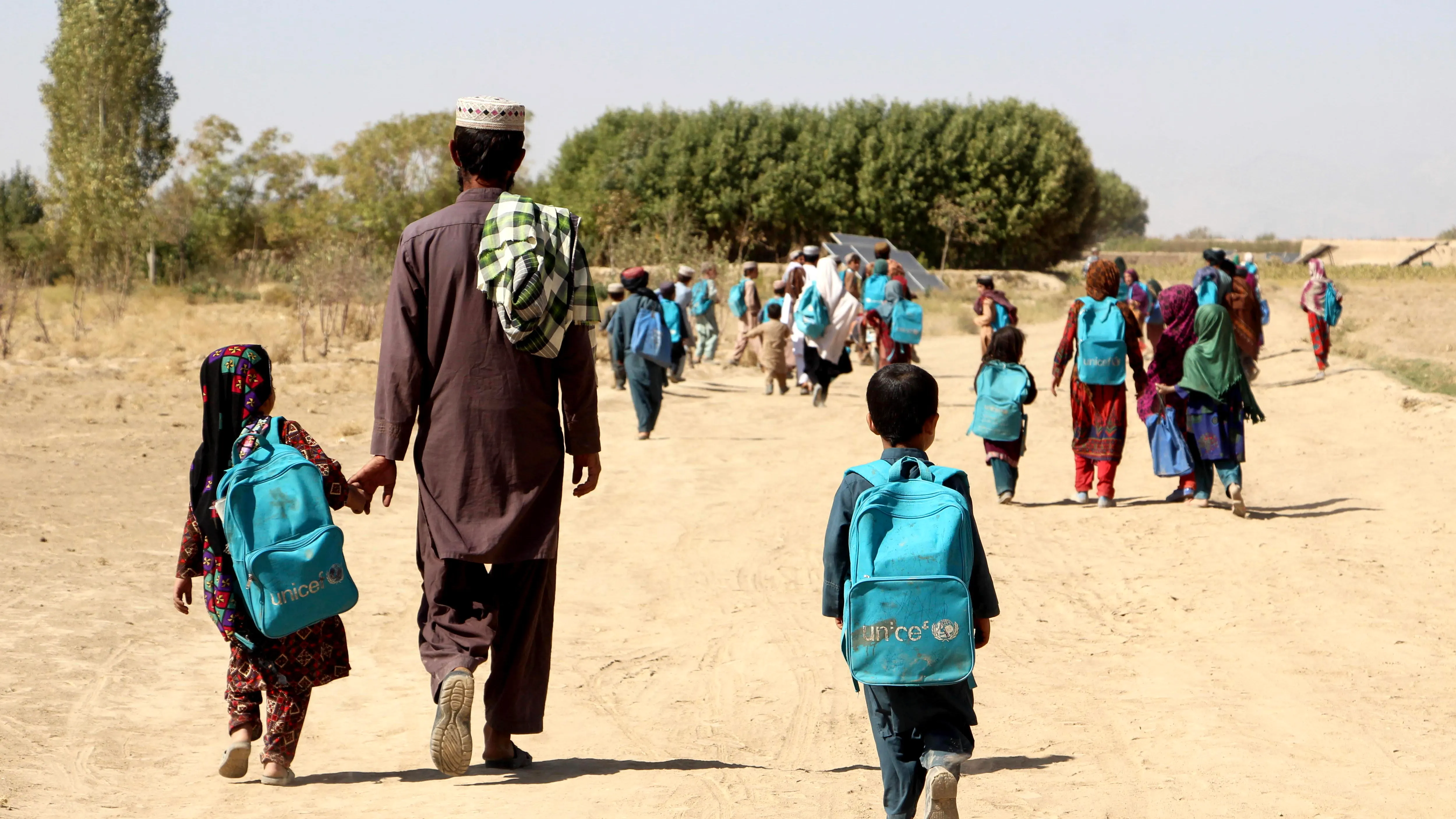 Niiños y niñas afganos regresan a casa después de asistir a una clase al aire libre debido a la falta de un edificio escolar, en la aldea de Barwai del distrito de Arghandab, provincia de Zabul, Afganistán,