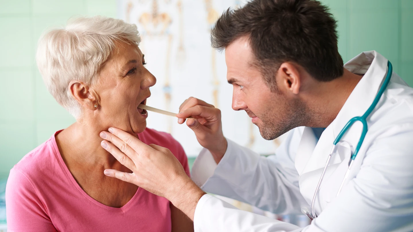 Una médico mirando la garganta a una paciente. Una médico mirando la garganta a una paciente.