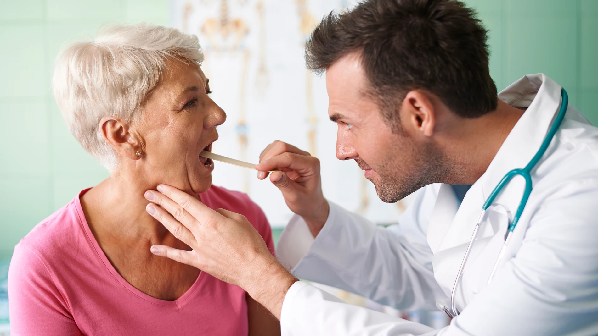 Una médico mirando la garganta a una paciente.