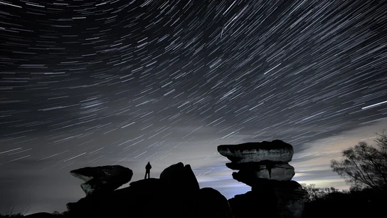 Un hombre observa un meteoro durante la lluvia de estrellas Gemínidas sobre Brimham Rocks. Un hombre observa un meteoro durante la lluvia de estrellas Gemínidas sobre Brimham Rocks.