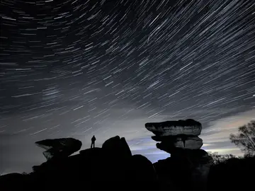 Un hombre observa un meteoro durante la lluvia de estrellas Gemínidas sobre Brimham Rocks.