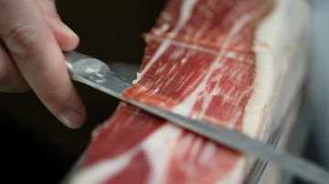 Un cortador profesional con un jamón ibérico Cinco Jotas Un cortador profesional con un jamón ibérico Cinco Jotas
