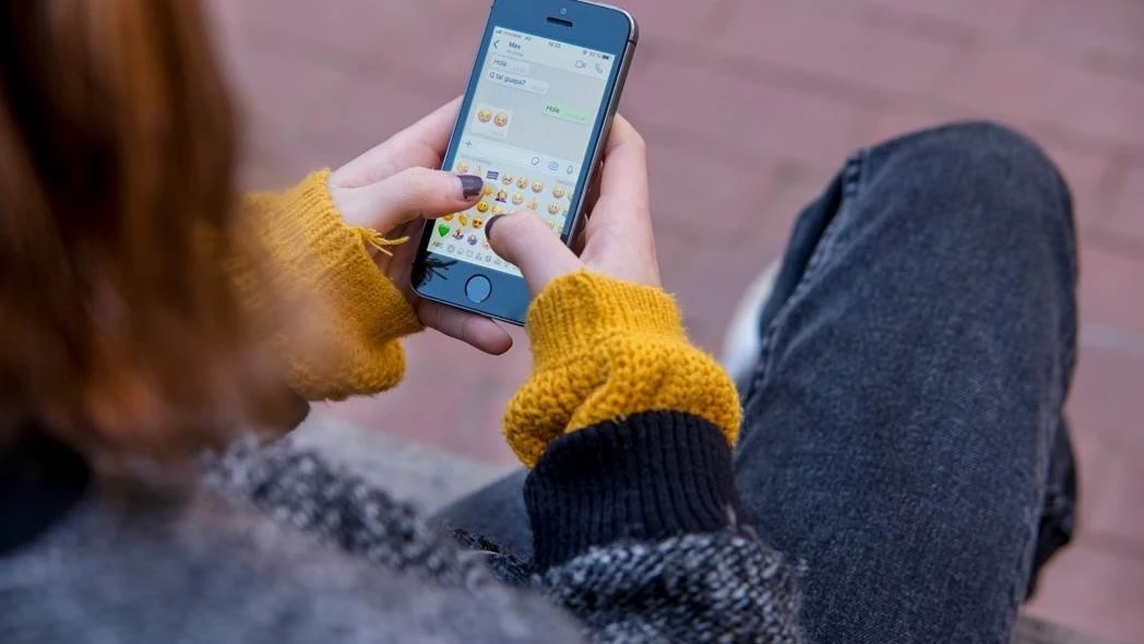 Adolescente con un teléfono móvil en mano. 