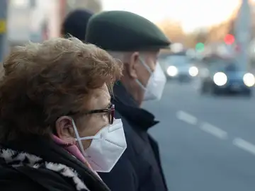 Una pareja de ancianos con mascarillas esperando para cruzar una calle en Madrid