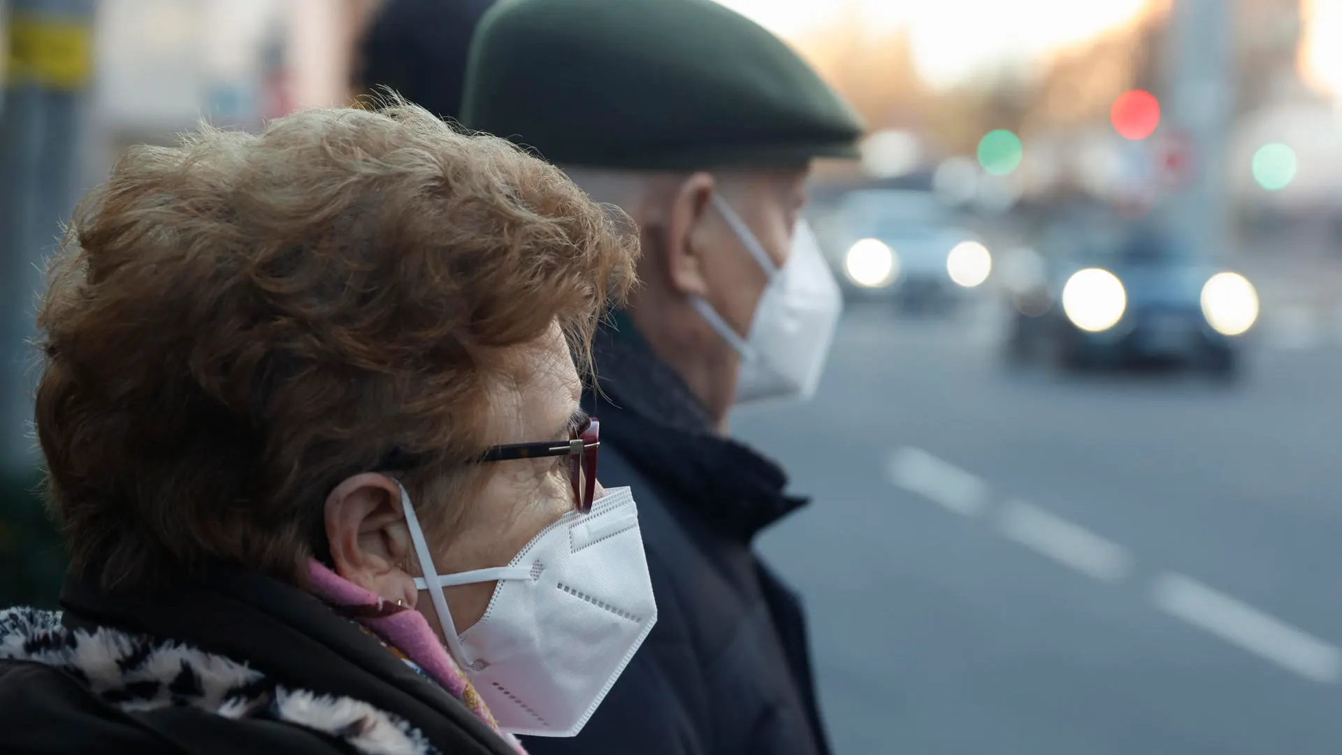 Una pareja de ancianos con mascarillas esperando para cruzar una calle en Madrid