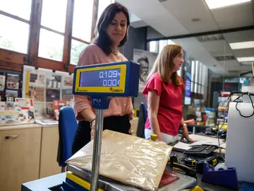 Una trabajadora pesa un paquete para enviar, en una oficina de Correos, a 23 de octubre de 2023, en Valencia.