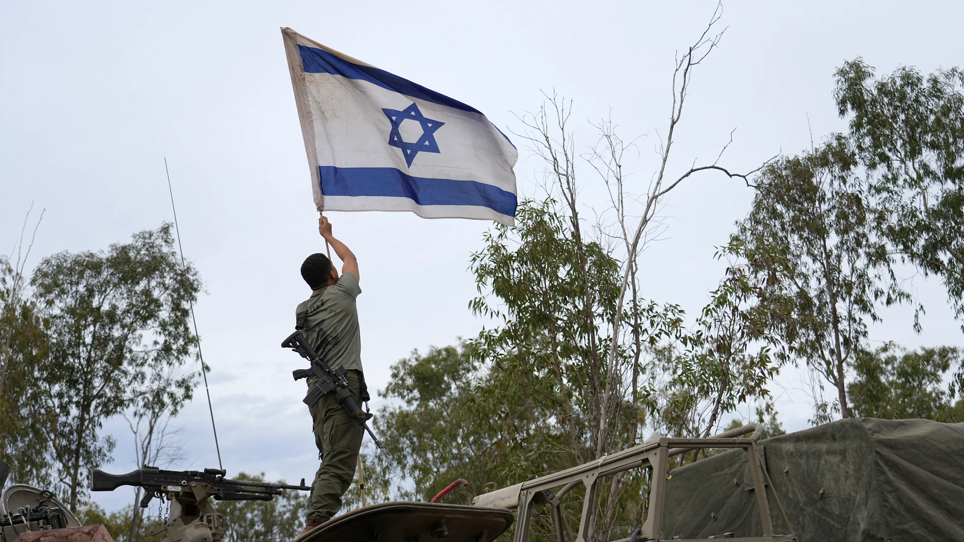 Un soldado israelí ondea la bandera de Israel cerca de la frontera con la Franja de Gaza