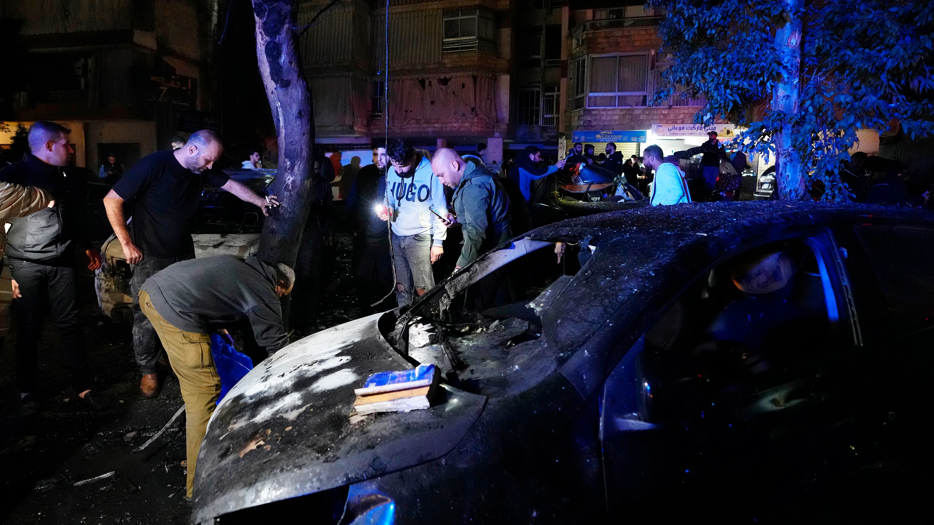 Personas inspeccionando partes de cuerpos tras una explosión masiva en el suburbio sur de Beirut, Líbano