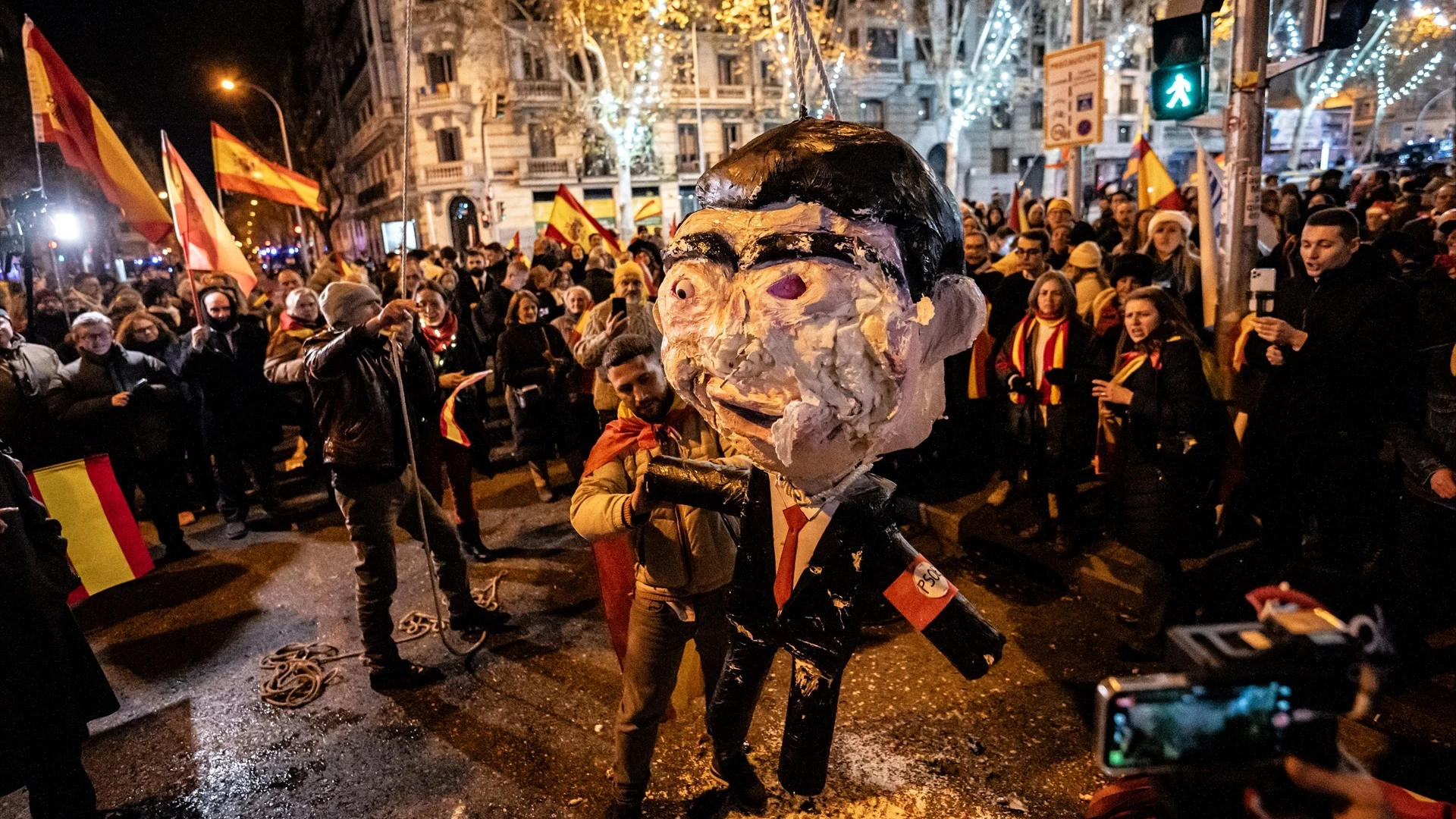 Uno de los manifestantes golpea el muñeco que simula ser Pedro Sánchez en la protesta del 31 de diciembre en la calle Ferraz.