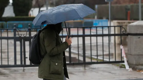 Imagen de archivo de una persona paseando bajo la lluvia con un paraguas. Imagen de archivo de una persona paseando bajo la lluvia con un paraguas.