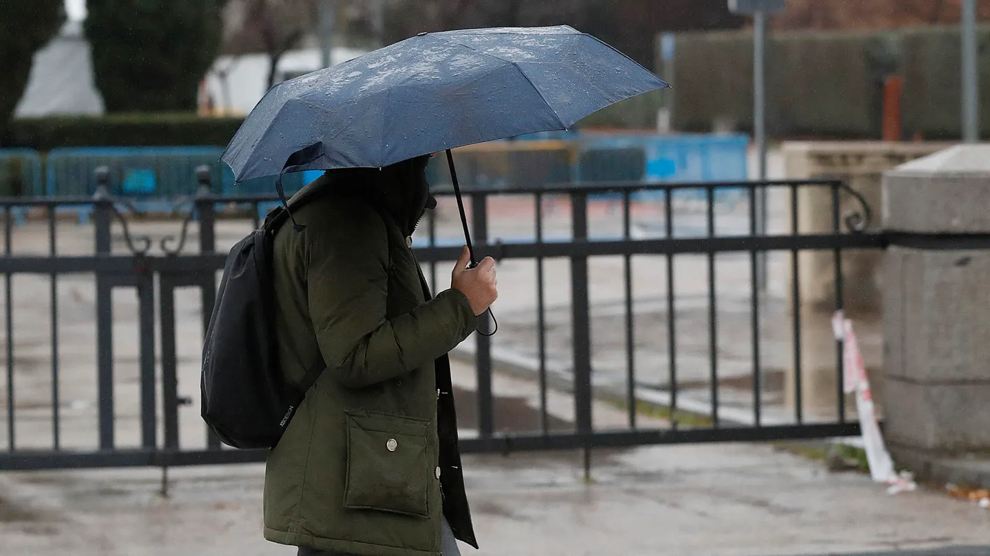 Imagen de archivo de una persona paseando bajo la lluvia con un paraguas. Imagen de archivo de una persona paseando bajo la lluvia con un paraguas.