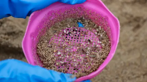 Una voluntaria recogía pellets de plástico este lunes en la playa coruñesa de O Portiño