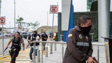 Policías persiguen a un presunto delincuente a pocas cuadras de la sede del canal de televisión TC, donde encapuchados armados ingresaron y sometieron a su personal durante una transmisión en vivo.