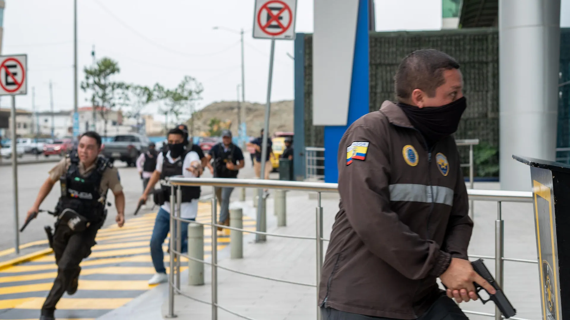 Policías persiguen a un presunto delincuente a pocas cuadras de la sede del canal de televisión TC, donde encapuchados armados ingresaron y sometieron a su personal durante una transmisión en vivo.