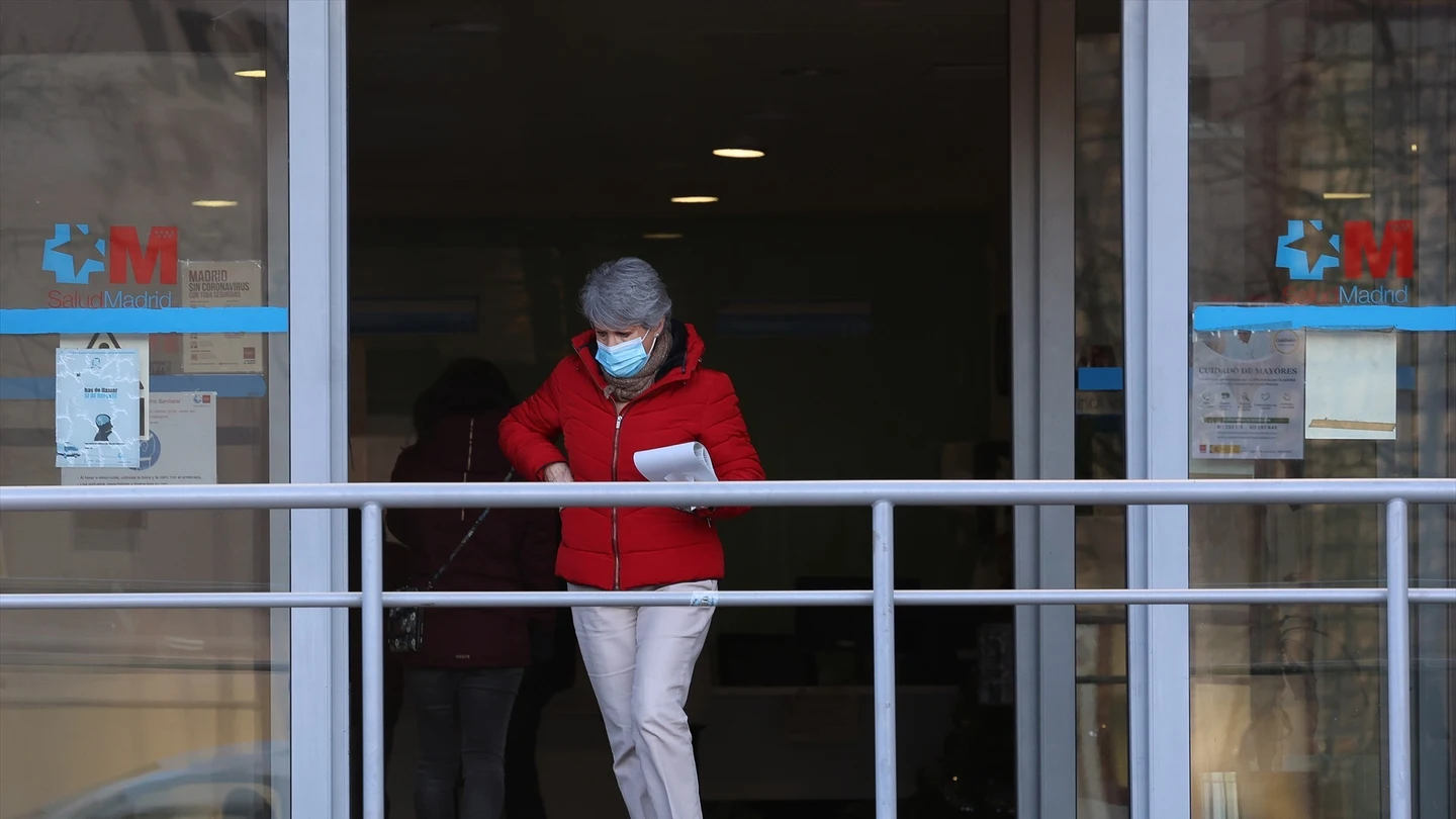 Una mujer con una mascarilla en la cara a su salida de un centro de salud Una mujer con una mascarilla en la cara a su salida de un centro de salud