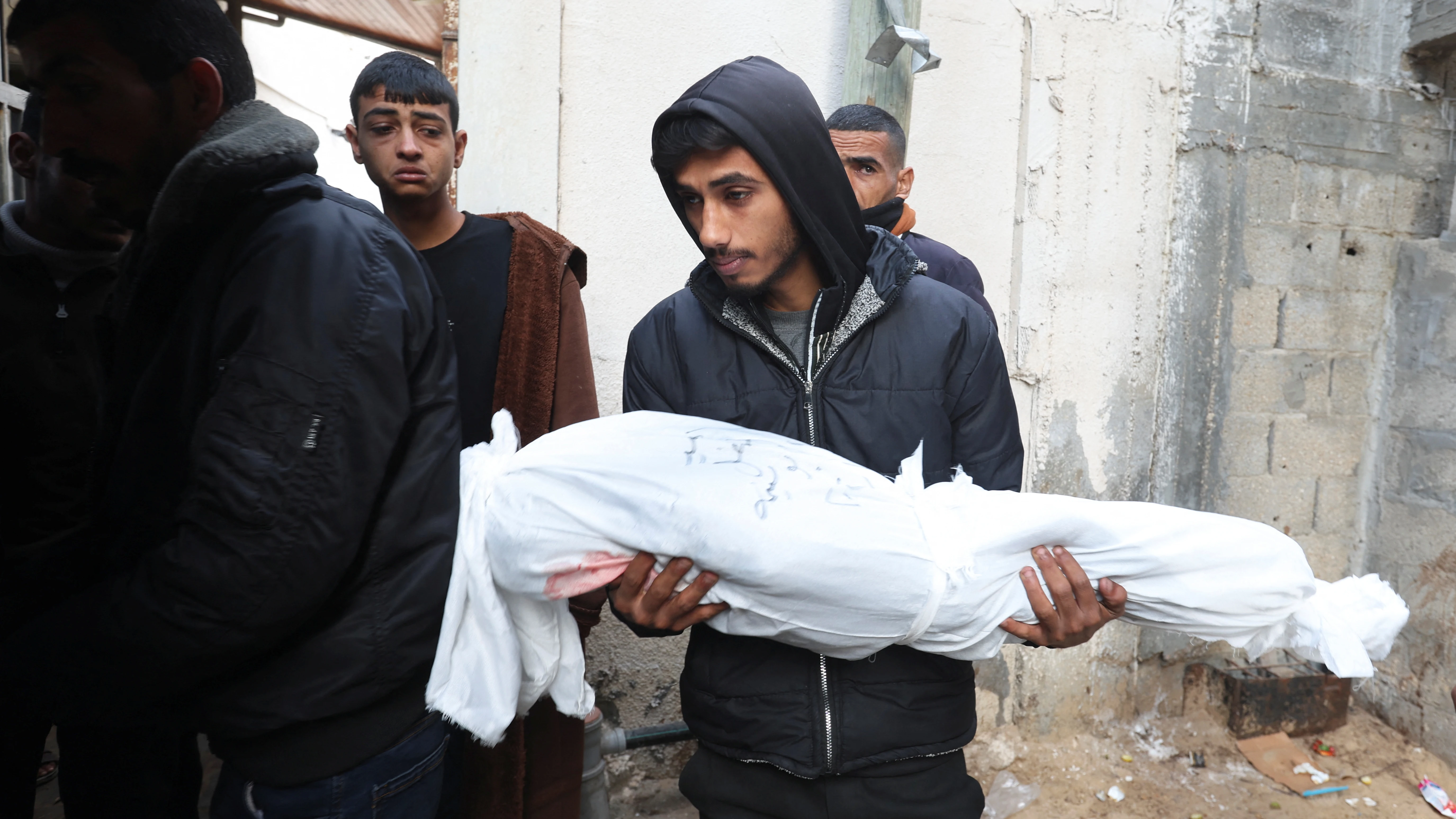 Un hombre lleva el cuerpo de una víctima palestina muerta en un ataque israelí en el hospital Abu Yousef al-Najjar, en Rafah, en el sur de la Franja de Gaza, este 12 de enero.