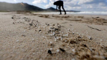 Una persona recoge pellets este jueves, en la playa de Traba, situada en el concello coruñés de Laxe