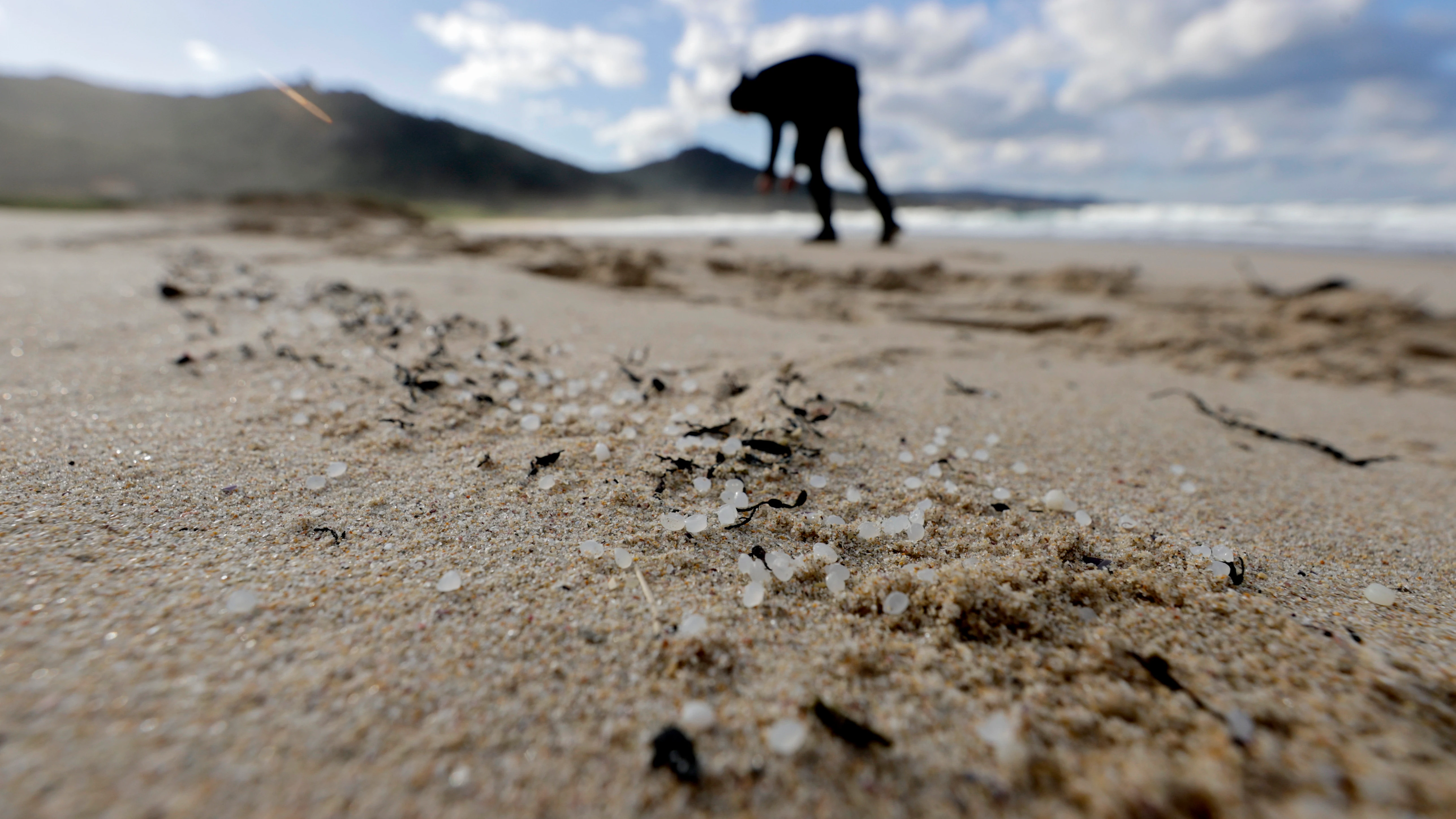 Una persona recoge pellets este jueves, en la playa de Traba, situada en el concello coruñés de Laxe