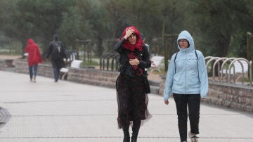 Dos personas caminan bajo la lluvia en la playa de Ondarreta, a 14 de octubre de 2023, en San Sebastián, Guipúzcoa.