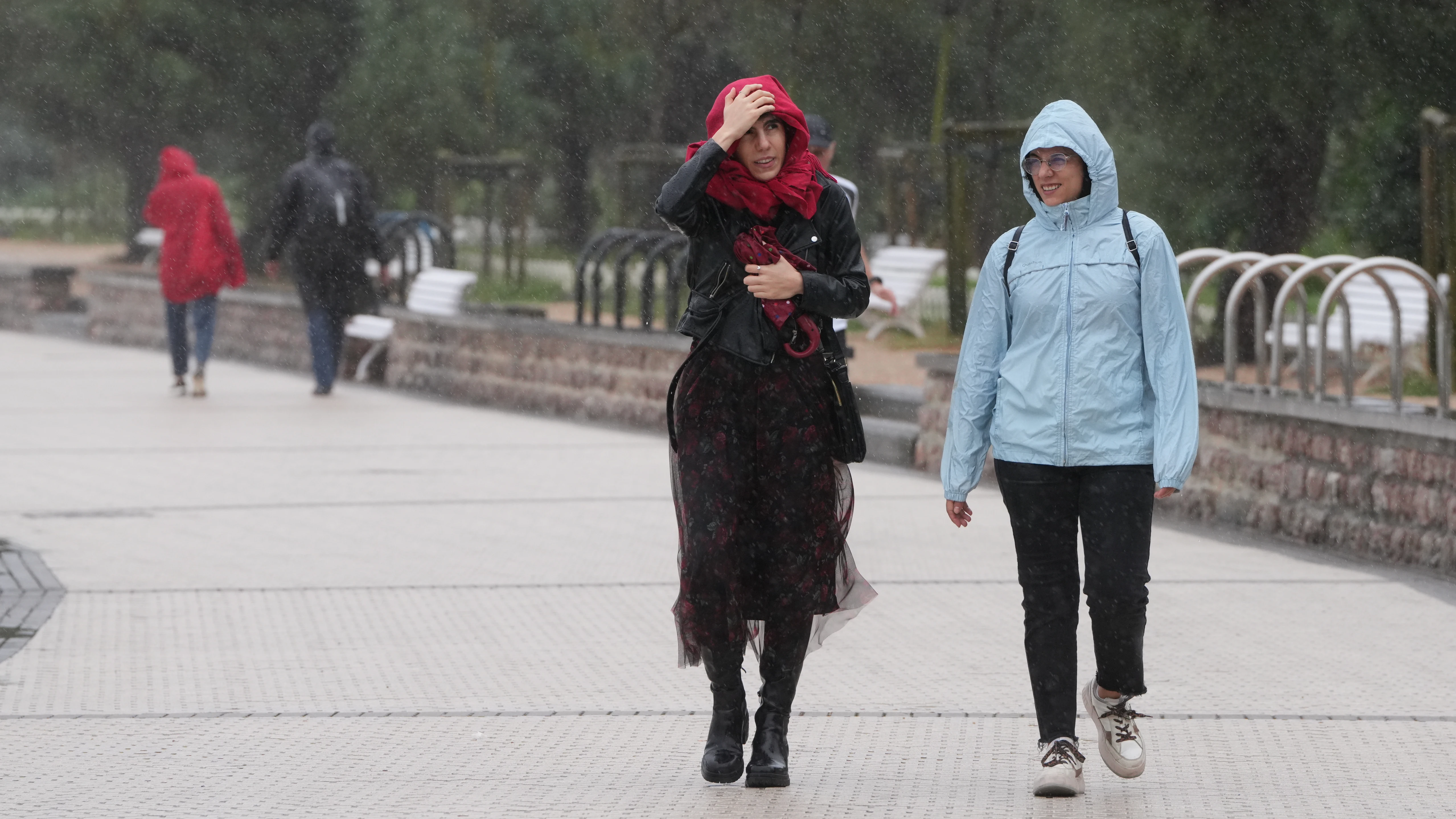 Dos personas caminan bajo la lluvia en la playa de Ondarreta, a 14 de octubre de 2023, en San Sebastián, Guipúzcoa.