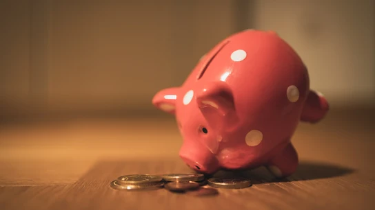 Unas monedas junto a una hucha con forma de cerdito. Unas monedas junto a una hucha con forma de cerdito.