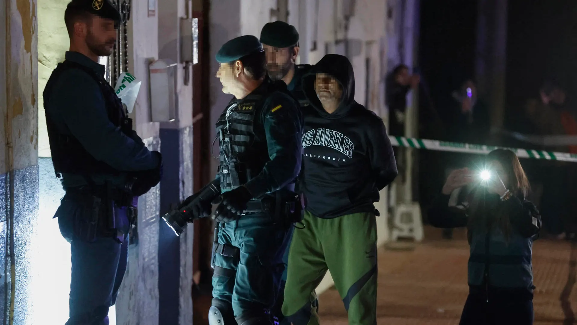 El presunto asesino de tres hermanos en Morata de Tajuña llega custodiado por guardias civiles al registro de su vivienda.