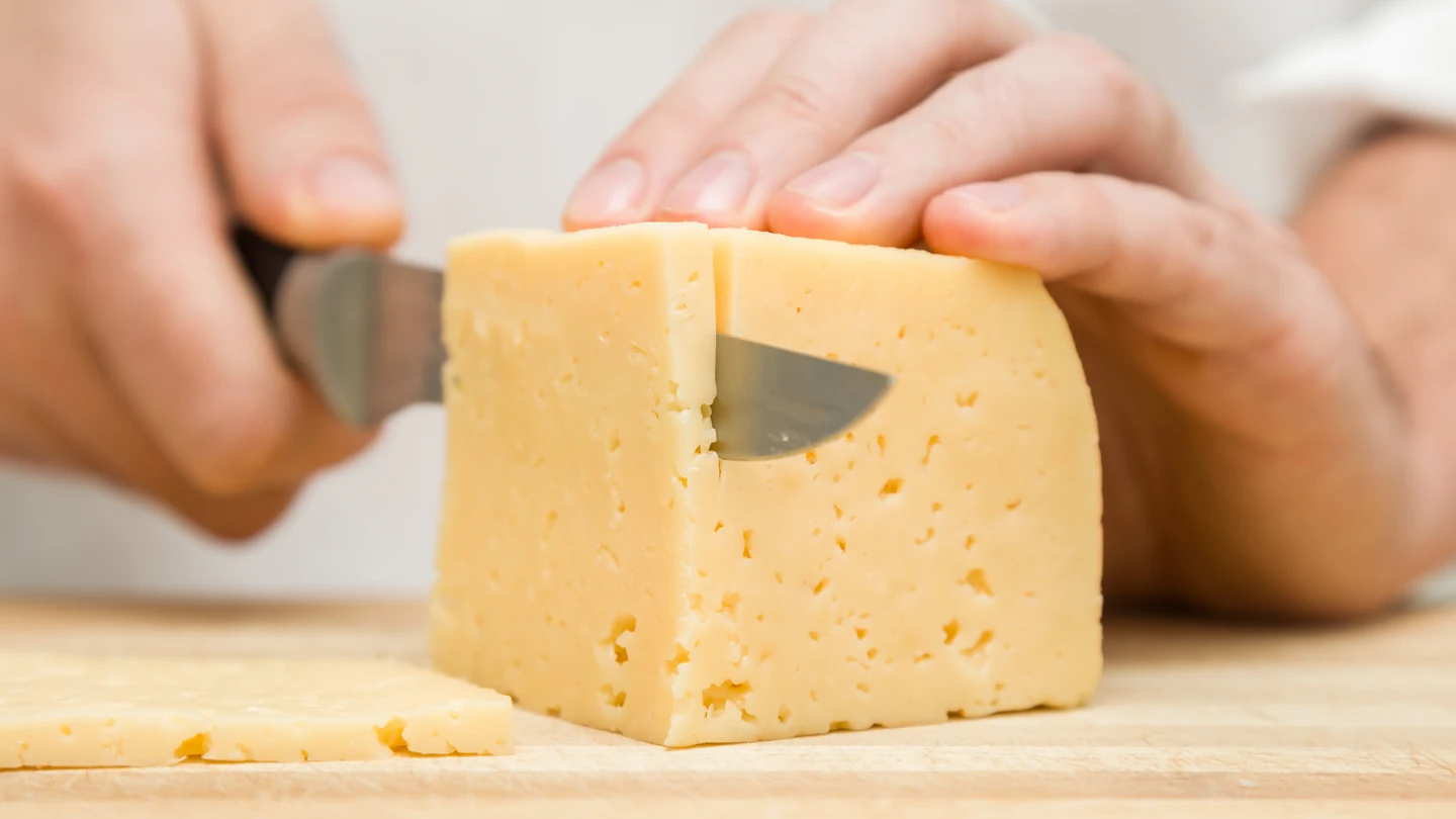 Imagen de archivo de un chef cortando queso Imagen de archivo de un chef cortando queso