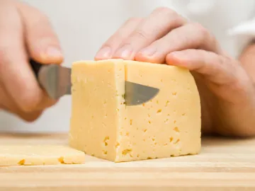 Imagen de archivo de un chef cortando queso Imagen de archivo de un chef cortando queso