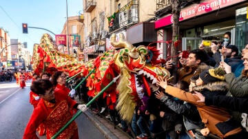 Varias personas acercan un dragón a la gente durante la celebración del pasacalles del Año Nuevo Chino 2023, en el distrito de Usera, a 22 de enero de 2023, en Madrid (España). 