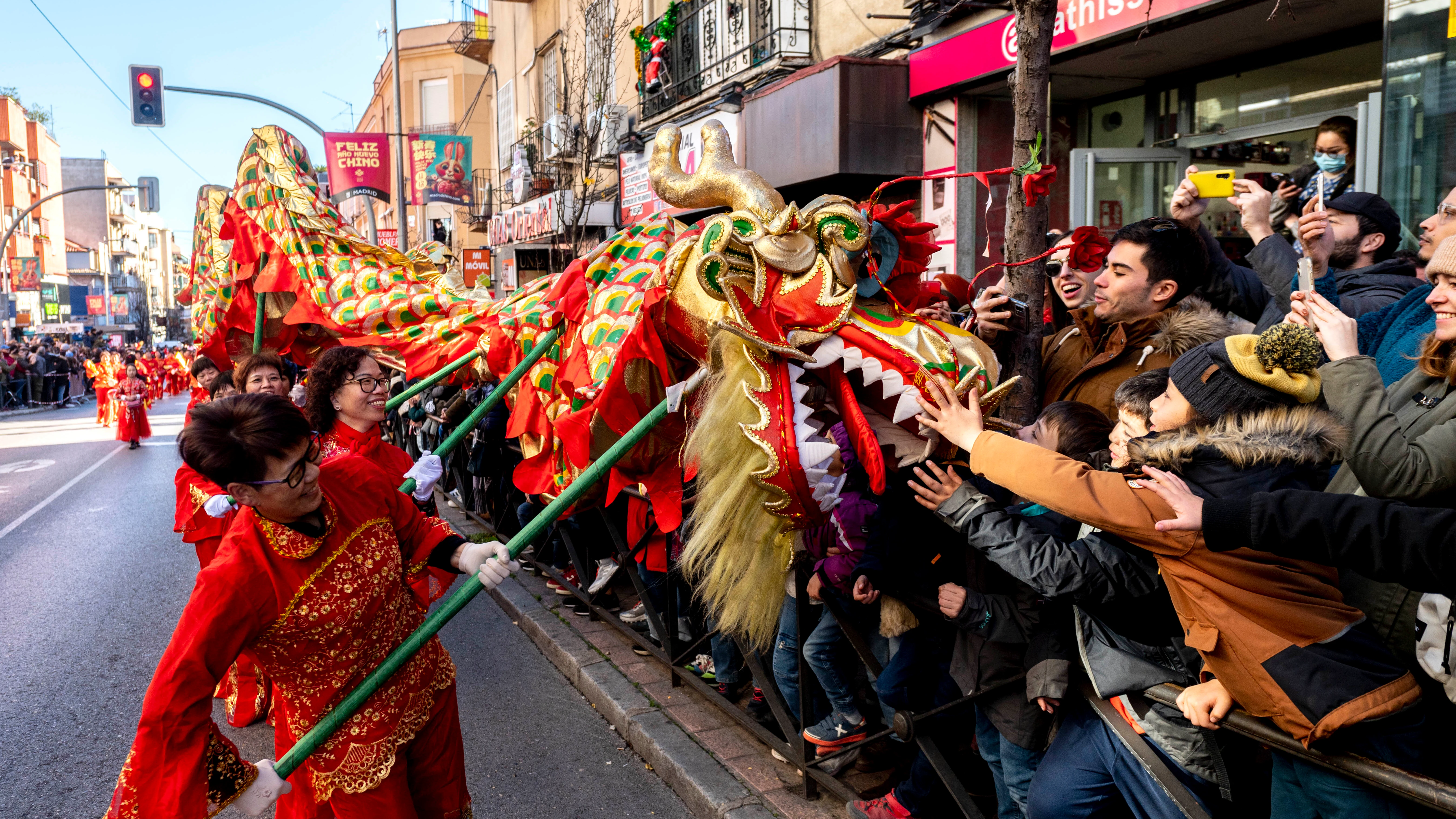 Varias personas acercan un dragón a la gente durante la celebración del pasacalles del Año Nuevo Chino 2023, en el distrito de Usera, a 22 de enero de 2023, en Madrid (España). 