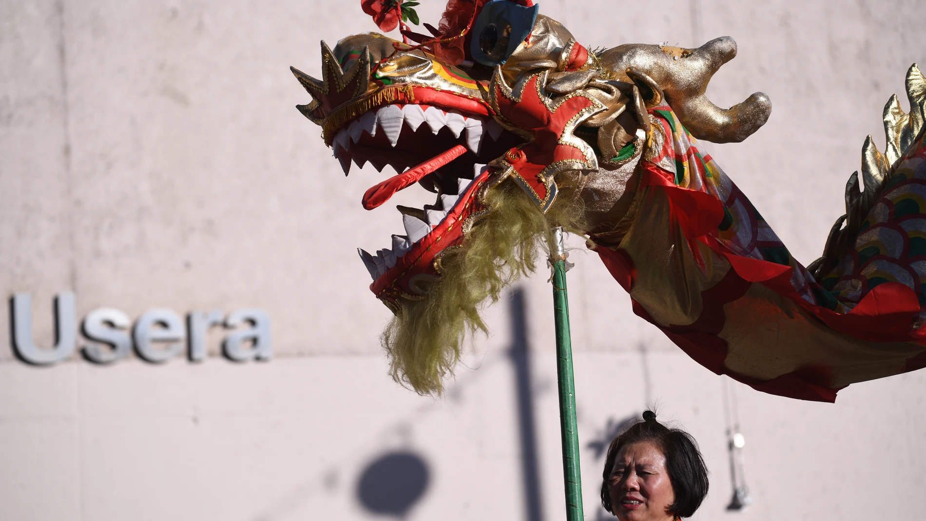 Una mujer sujeta la cabeza de un dragón durante las celebraciones del Año Nuevo Chino en la plaza de Distrito de Usera, a 20 de enero de 2023.