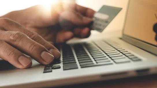 Persona usando un ordenador con tarjeta de crédito y haciendo compras online. Persona usando un ordenador con tarjeta de crédito y haciendo compras online.