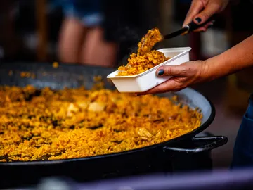 Mujer sirviendo una paella en platos Mujer sirviendo una paella en platos