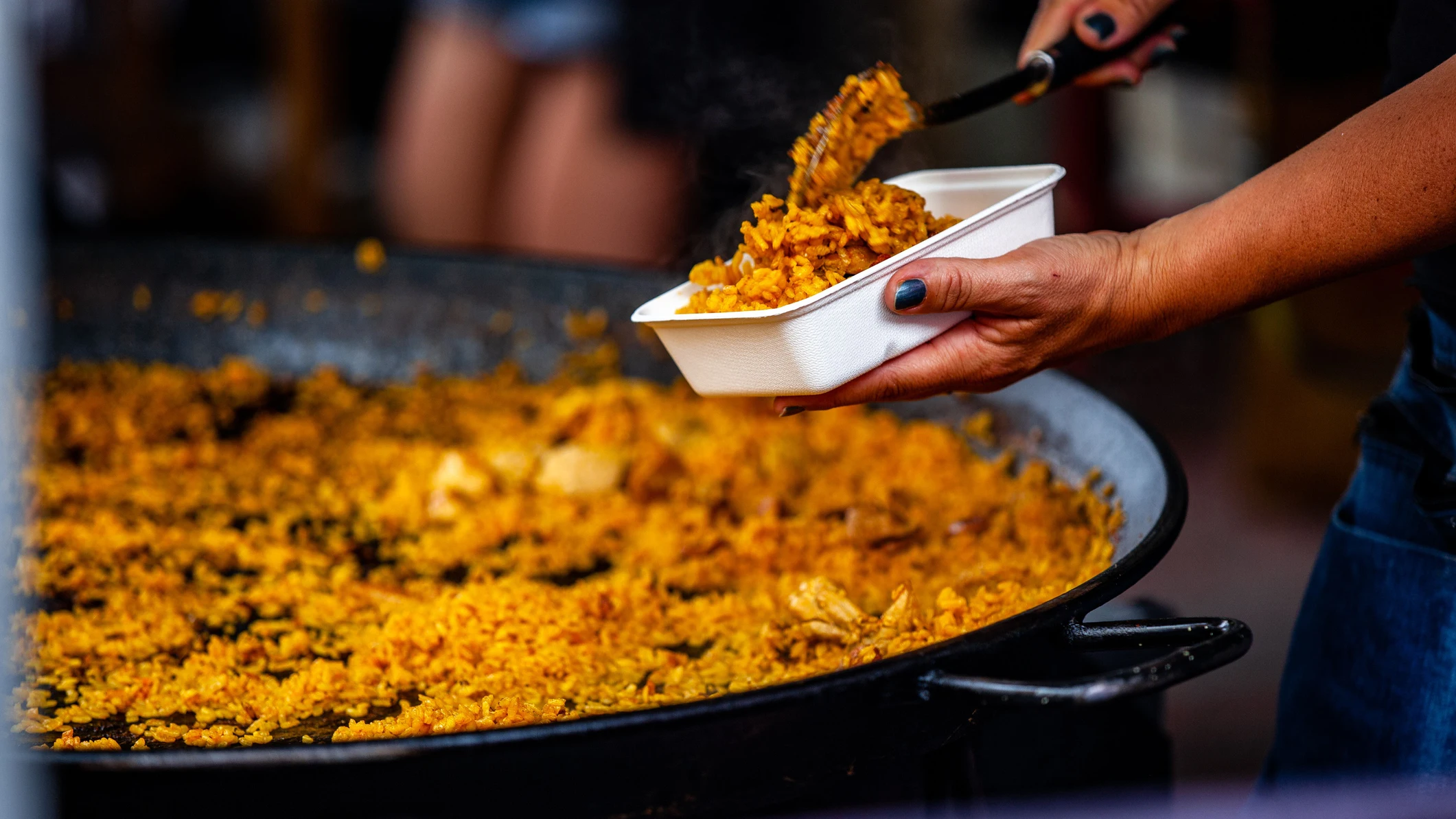 Mujer sirviendo una paella en platos Mujer sirviendo una paella en platos