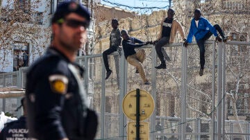 Simulación de cuatro migrantes saltando la Valla de Melilla, en la Plaza del Ayuntamiento de Valencia
