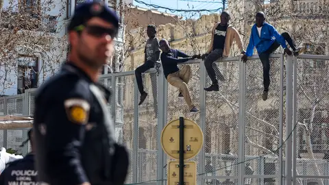 Simulación de cuatro migrantes saltando la Valla de Melilla, en la Plaza del Ayuntamiento de Valencia