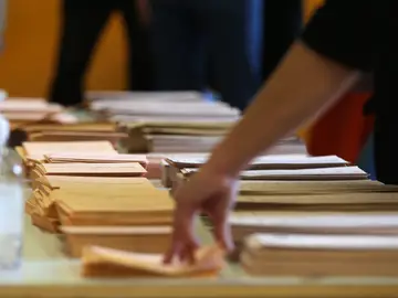 Una persona coge un sobre para votar en la última hora de la jornada en el Colegio Pi i Margall, a 4 de mayo de 2021, en Madrid (España).