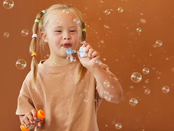 Niña con síndrome de down soplando burbujas Niña con síndrome de down soplando burbujas