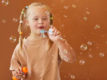 Niña con síndrome de down soplando burbujas Niña con síndrome de down soplando burbujas