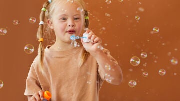 Niña con síndrome de down soplando burbujas