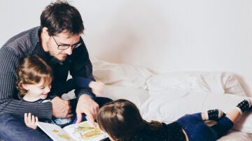 Un padre leyendo con sus hijos/as.
