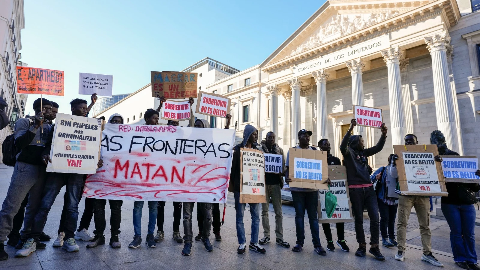 Manifestantes ante el Congreso de los Diputados este martes con motivo de la votación a la iniciativa legislativa popular que regulará la situación de medio millón de migrantes en España.