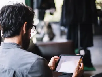 Un hombre leyendo en una tablet. 