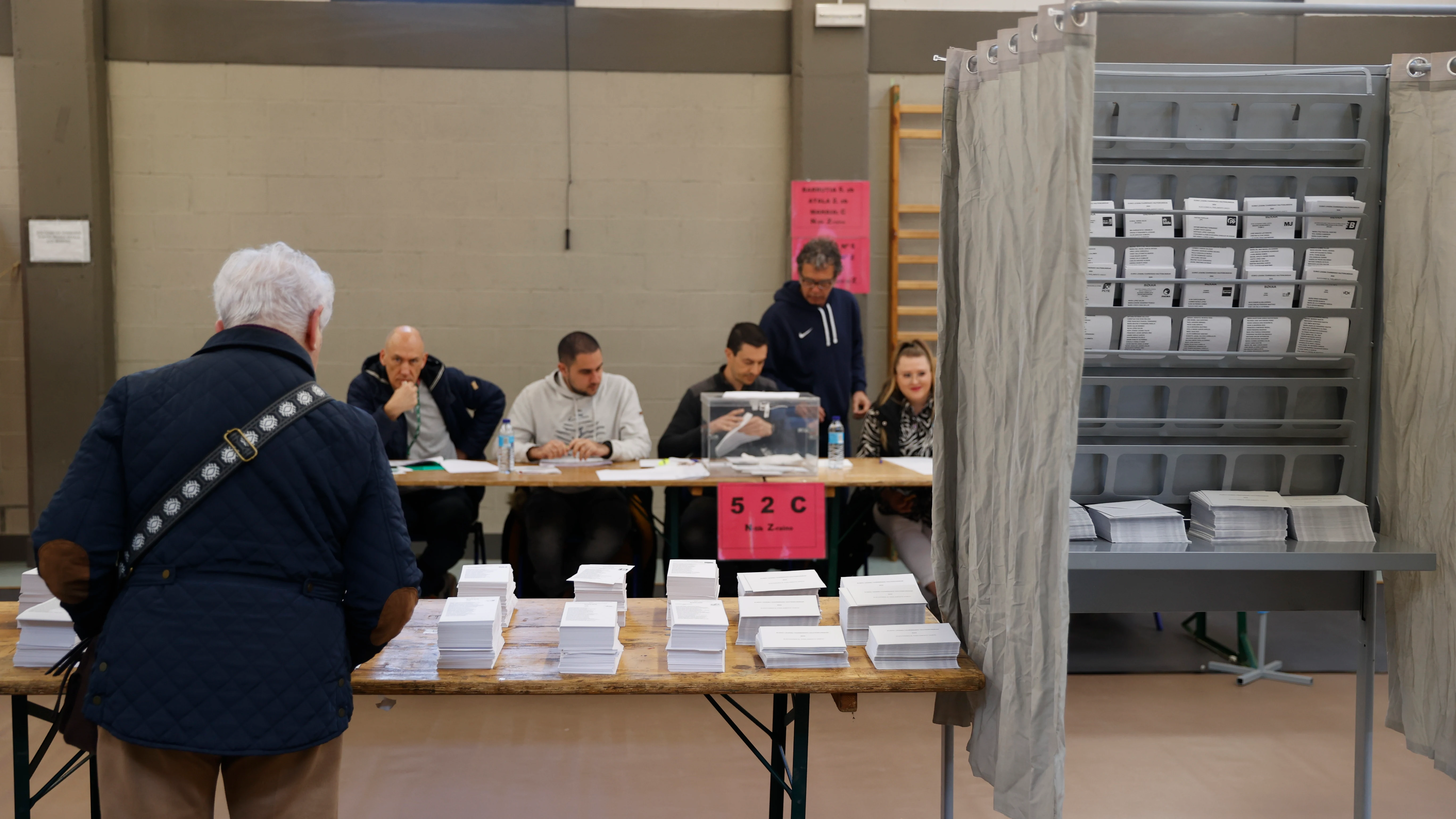 Un hombre escoge papeleta para ejercer su derecho al voto en las elecciones vascas de 2024