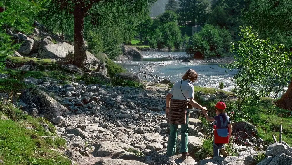 Madre con su hijo junto al río en montaña