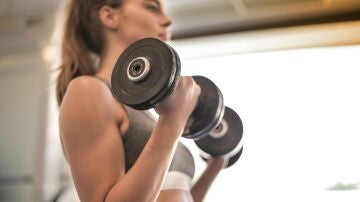 Una mujer entrena fuerza con pesas.
